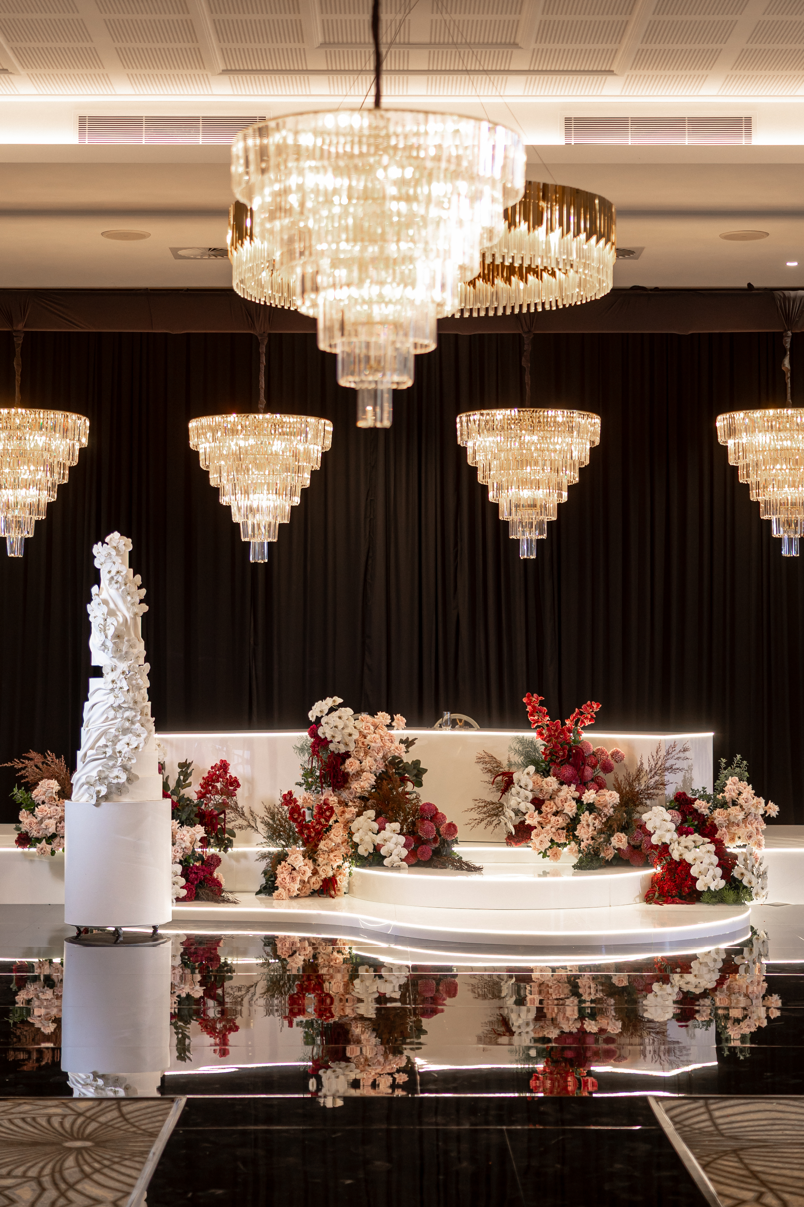 Luxury wedding cake display with floral centrepiece and crystal chandeliers